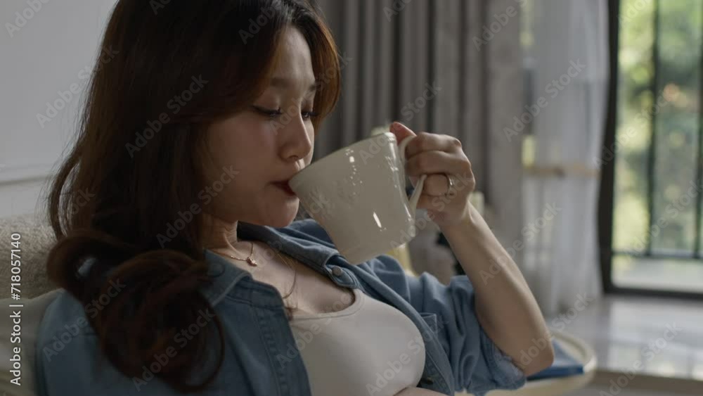 asiatic Chinese oriental young pregnant woman sitting on her bed drinking a cup of coffee health pregnancy motherhood procreation concept. asiatic Chinese oriental young pregnant woman sitting on her bed drinking a cup of coffee health pregnancy motherhood procreation concept.