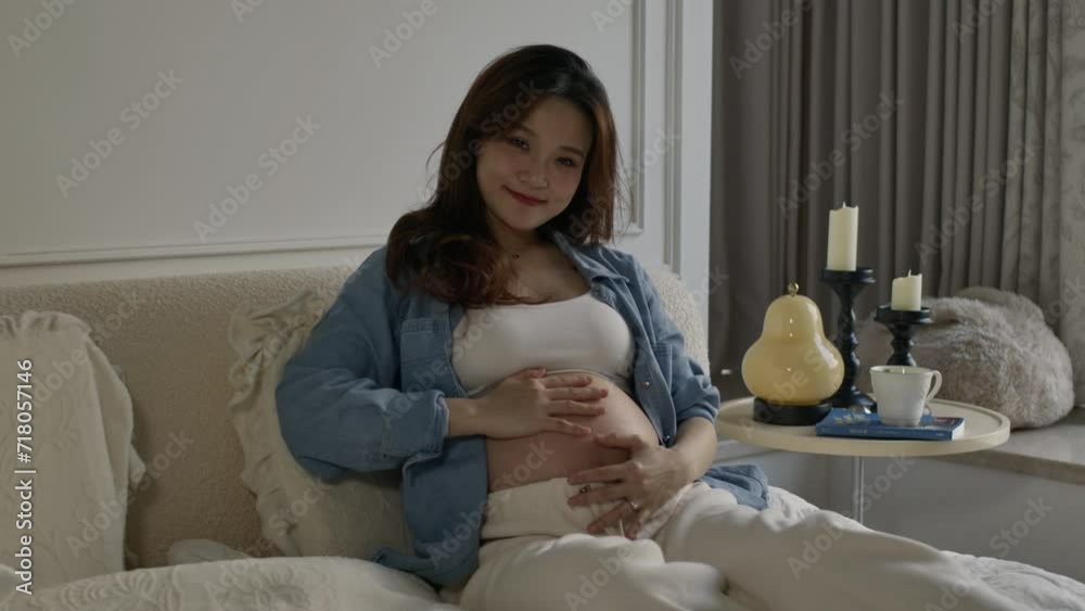 asiatic young pregnant woman touching her big belly waiting for a newborn baby. pregnant woman holding her belly