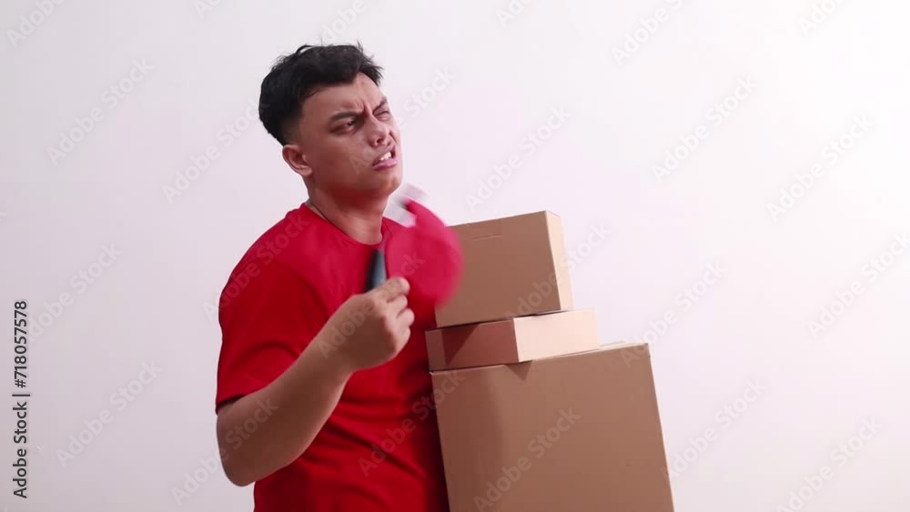 Sad Young asian courier man holding cardboards and feeling hot weather in the summer day in studio