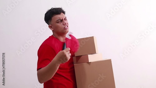 Sad Young asian courier man holding cardboards and feeling hot weather in the summer day in studio photo