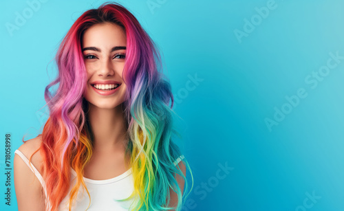 Girl with multicoloured hair rainbow hair at laughing girl on blue background