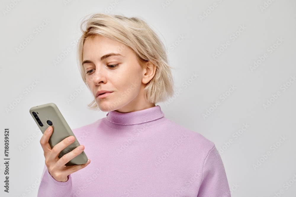 Portrait of young blond woman holding mobile phone in hand with happy smiling face. Person with smartphone isolated on white background. Portrait of young blond woman holding mobile phone in hand with happy smiling face. Person with smartphone isolated on white background.