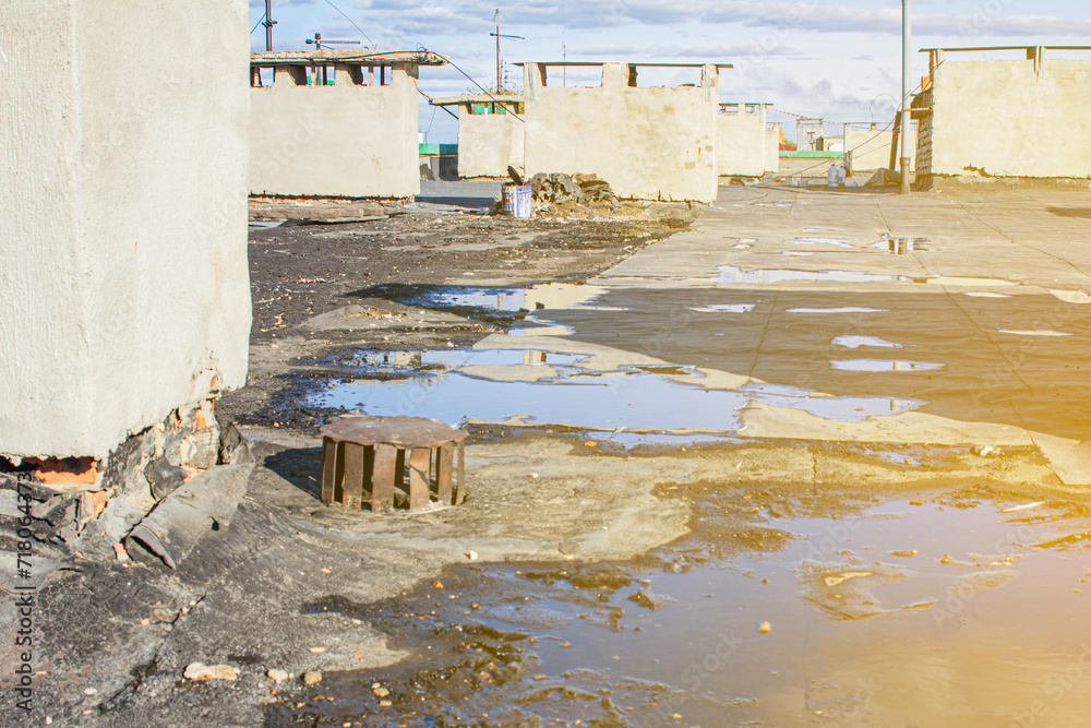 storm drain on a bitumen roof and rain puddles on an old unrepaired roof, the problem of leakage of old housing stock