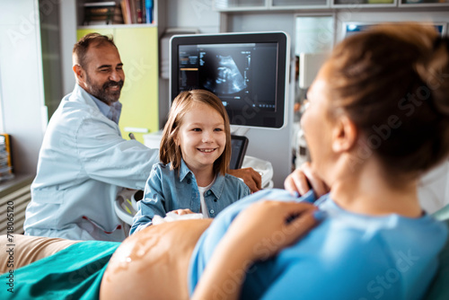 Little girl holding pregnant mothers belly during examination