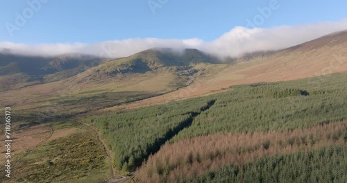 Drone cinematic flying over forestry plantation to mountains Comeragh Mountains Waterford Ireland winter day photo
