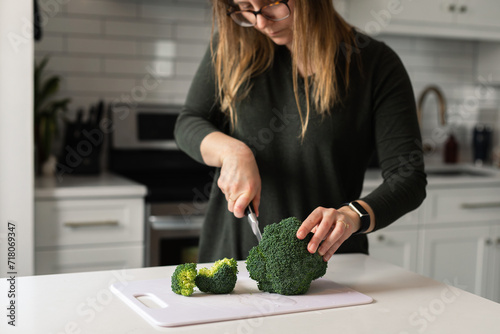 woman chopping fresh broccoli in the kitchen