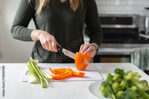 slicing an orange bell pepper for vegan dinner photo