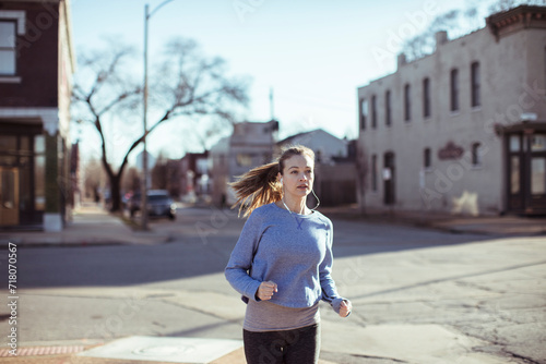 Young woman jogging through a suburban neighborhood on a sunny day