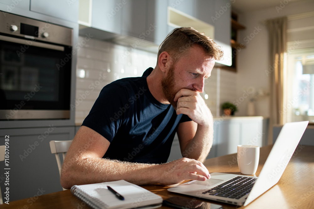 Man working on laptop at home with coffee and notebook Man working on laptop at home with coffee and notebook