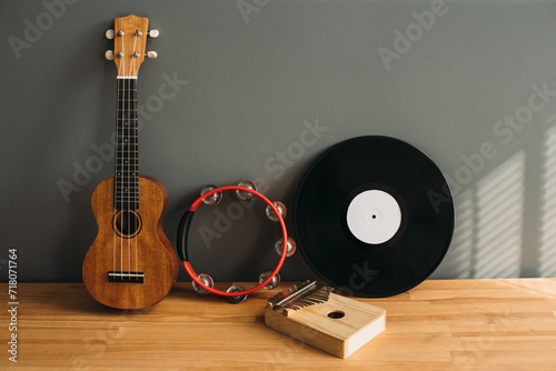 Still life on a musical theme, various musical instruments on a wooden table. Ukulele, tambourine, vinyl record and kalimba.