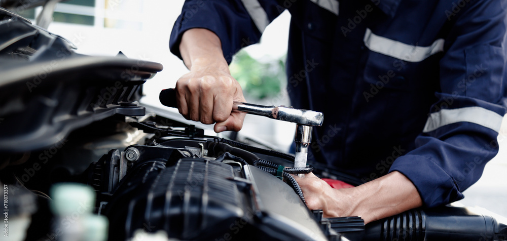 Mechanic are using the wrench to repair and maintenance auto engine at car repair shop,Car auto services and maintenance check concept.