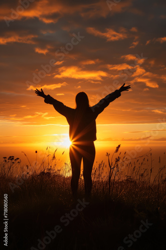 silhouette of a woman in sunset in nature with arms spread wide open
