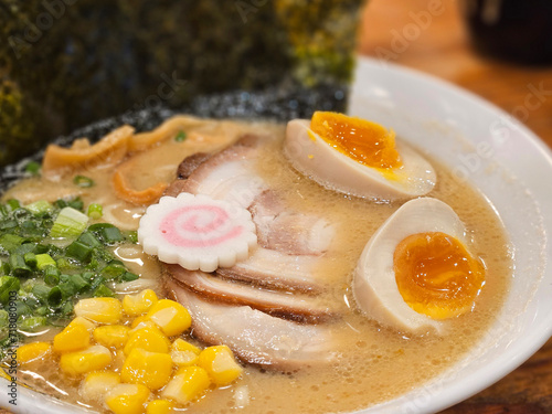 Closed up of miso base ramen Japanese style noodle with boiled eggs , pork sliced and corn with seaweed background