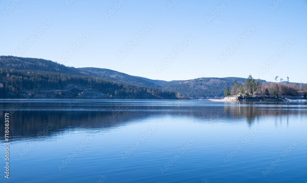 blue lake surrounded by forested hills 