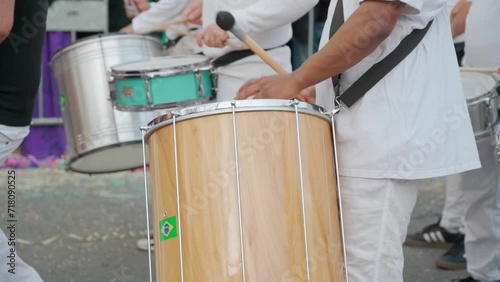 A group of drummers playing rhythmic sambo music during a carnival procession close-up dressed in white traditional suits. photo