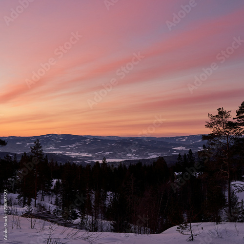 Spectacular sunset over the lake Krøderen with striped colorful clouds during the winter