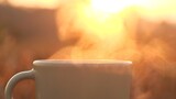 Close up coffee cup. Stunning steam rising from steaming mug of coffee set atop table against 4K outdoor nature scene in morning sunlight. Concept of hot coffee, tea, food, drink, espresso, breakfast