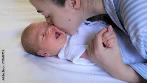 Portrait of a crying newborn baby. A young mother holds the baby by the hands, kisses and soothes him. Mental Health in Postpartum Time. Pregnancy And Depression.