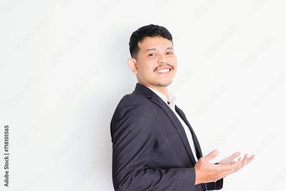 a young asian businessman stands and shows a gesture of pride and success