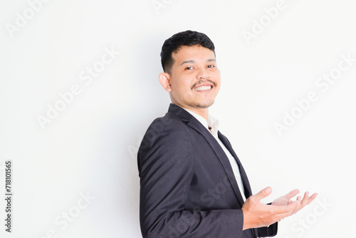 a young asian businessman stands and shows a gesture of pride and success