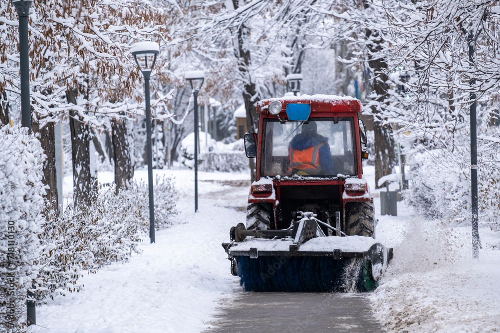 A tractor removes snow after a snowfall. Snow removal in the park. A tractor removes snow after a snowfall. Snow removal in the park.