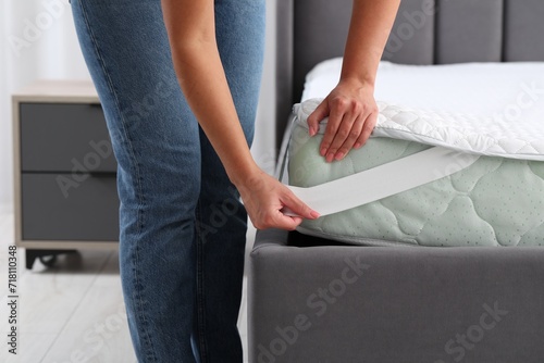 Foto Woman putting protector on mattress in bedroom, closeup