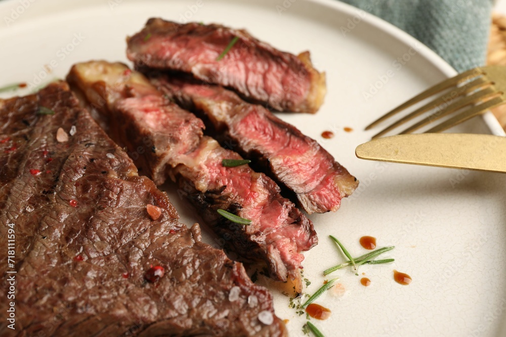 Delicious grilled beef steak with spices on plate, closeup