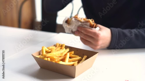 Man eating burger in restaurant enjoying delicious juicy hamburger and french fries 