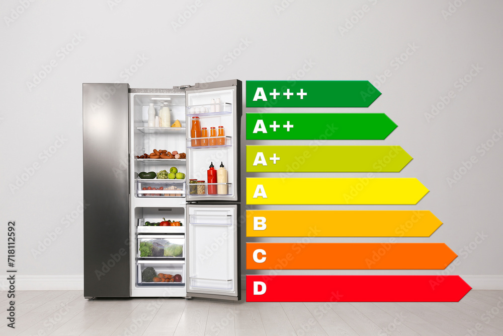 Energy efficiency rating label and open refrigerator near light wall indoors Energy efficiency rating label and open refrigerator near light wall indoors