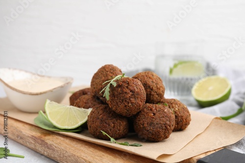 Delicious falafel balls, arugula, lime and sauce on table