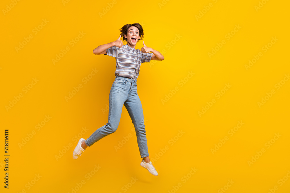 Full body photo of crazy impressed lady jump demonstrate thumb up empty space isolated on yellow color background