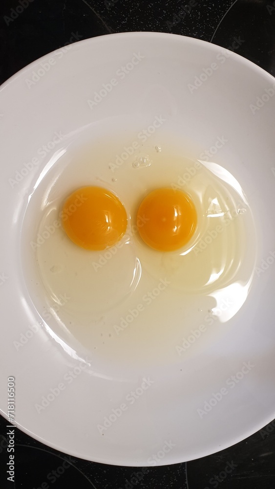 Preparing for omlette cooking with two raw eggs in a white plate. Preparing for omlette cooking with two raw eggs in a white plate.
