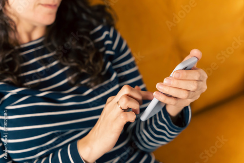 girl sits on the sofa and writes a chat message on a smartphone