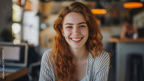 a red-haired modern pretty young woman smiles friendly in a coffee shop