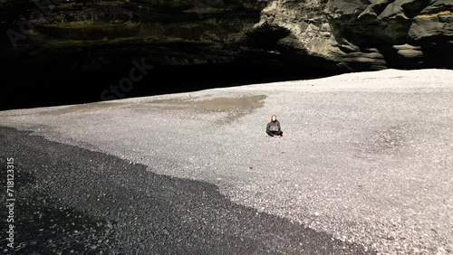 Girl freelancer sitting on the beach near the water with a computer working, view from a drone
