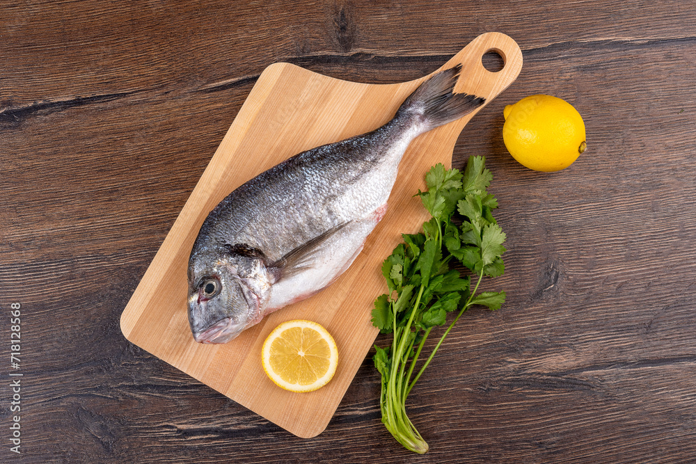 Top view of delicious raw dorado fish on a cutting board and lemon with cilantro.