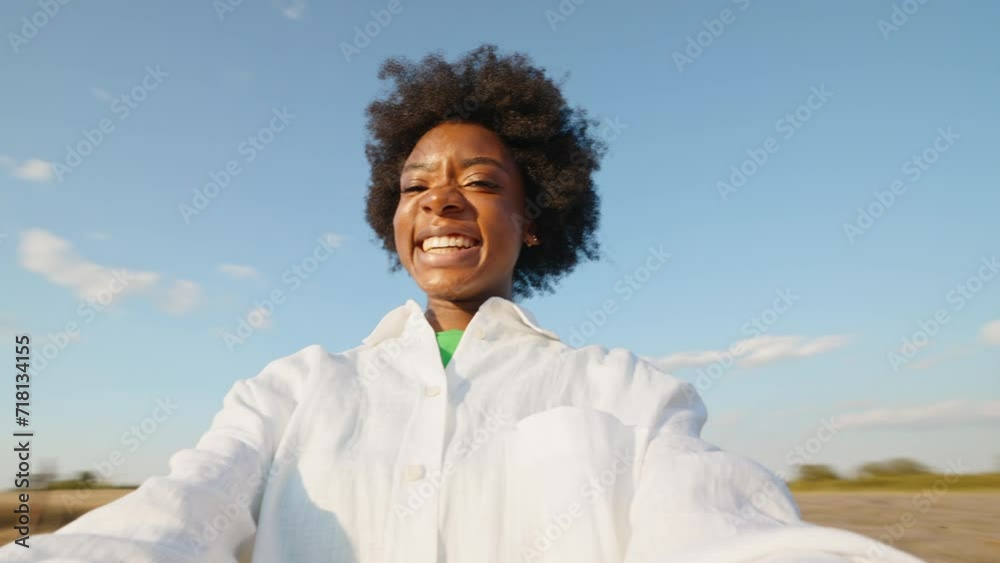 Portrait black woman afro hair smiling spinning looking at camera close up against blue clouds sky in summer on sunny day on walk. Freedom concept relax. Go Everywhere. Lifestyle. Positive emotions Portrait black woman afro hair smiling spinning looking at camera close up against blue clouds sky in summer on sunny day on walk. Freedom concept relax. Go Everywhere. Lifestyle. Positive emotions