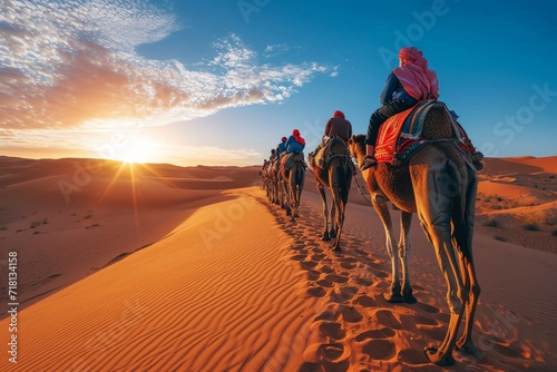 A nomadic tribe traverses the expansive sahara, their arabian camels carrying them through the singing sands and over towering dunes, as the sun sets over the aeolian landscape photo