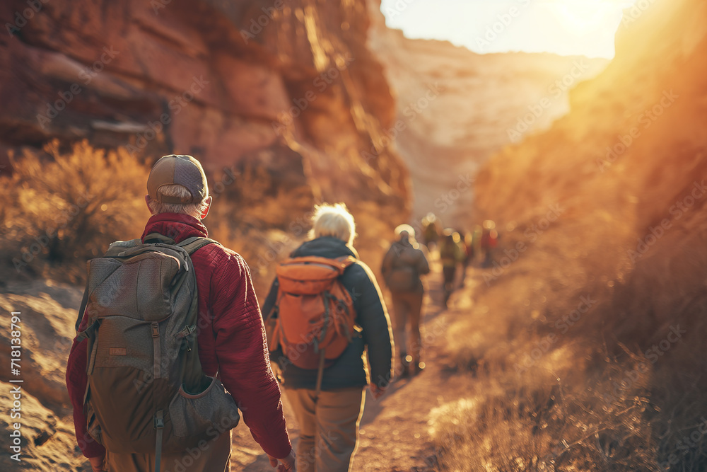 group of hikers is bathed in the golden light of the setting sun as they navigate through a rugged canyon trail. The warm glow of the evening sun highlights the red rock formations group of hikers is bathed in the golden light of the setting sun as they navigate through a rugged canyon trail. The warm glow of the evening sun highlights the red rock formations