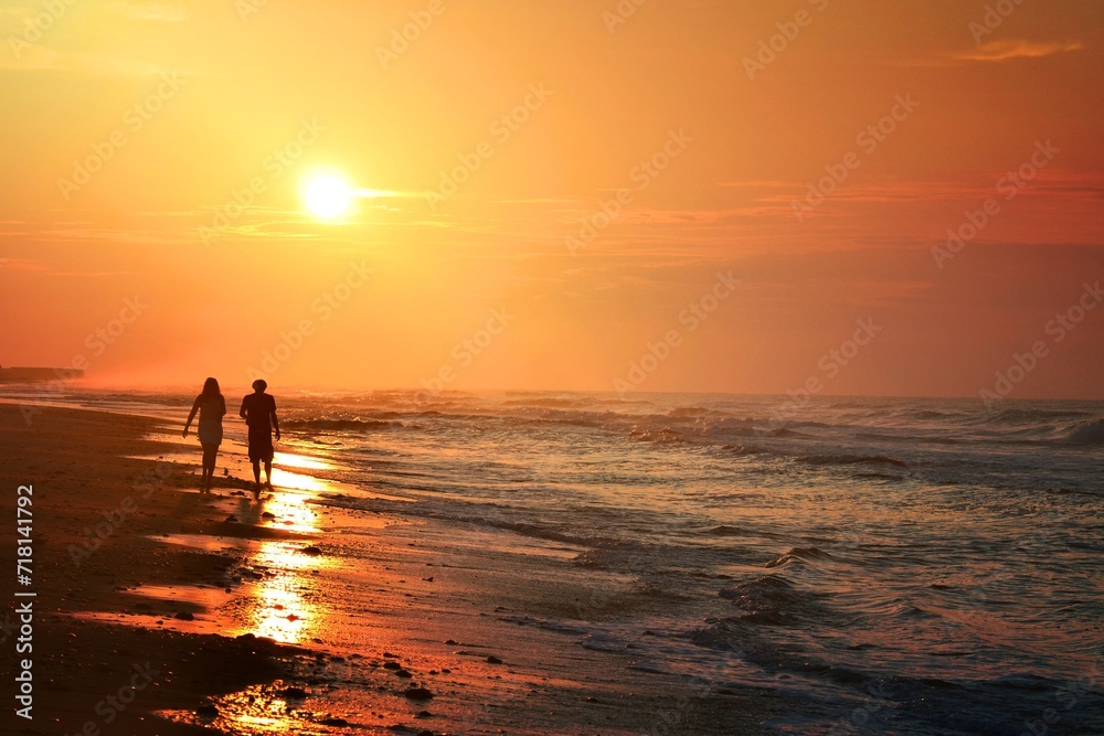 a silhouette of a young couple taking a walk along the beach at sunrise travel destination vacation