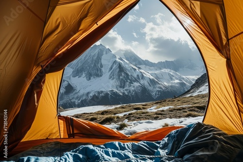 View from inside an open camping tent from the sleeping place to the beautiful snowy mountains landscape. Concept of mountaineering, tourist recreation and sport