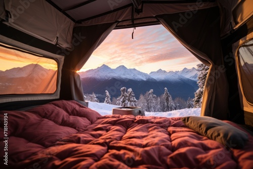 View from inside an open camping tent from the sleeping place to the beautiful snowy mountains landscape. Concept of mountaineering, tourist recreation and sport