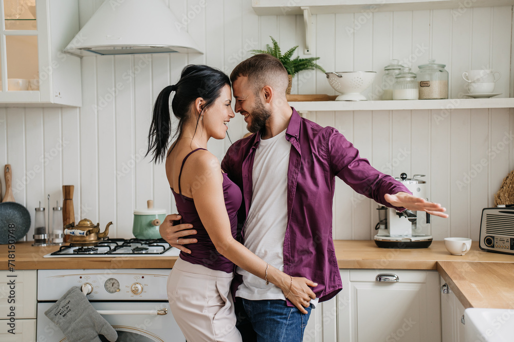 Happy couple dancing in kitchen, sharing a playful moment at home Happy couple dancing in kitchen, sharing a playful moment at home