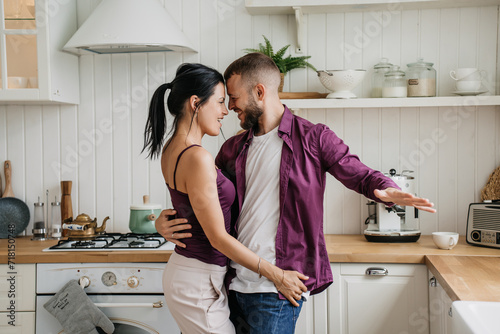 Happy couple dancing in kitchen, sharing a playful moment at home © Iona