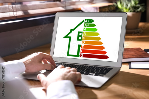 Energy efficiency. Man using laptop with colorful rating on display at table, closeup