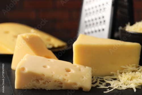 Grated and cut cheese on black table, closeup