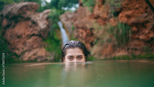 Woman peeping water surface at wilderness closeup. Wet hair brunette swimming