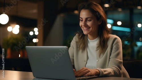 In a white shirt and black jacket, a young, beautiful woman in a white shirt and black jacket is using her laptop while smiling, talking on the phone, and working on documents.