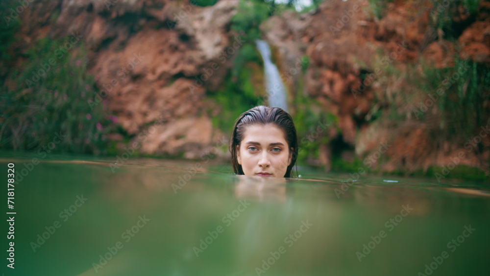 Fototapeta premium Attractive woman diving lagoon posing alone portrait. Seductive lady swimming