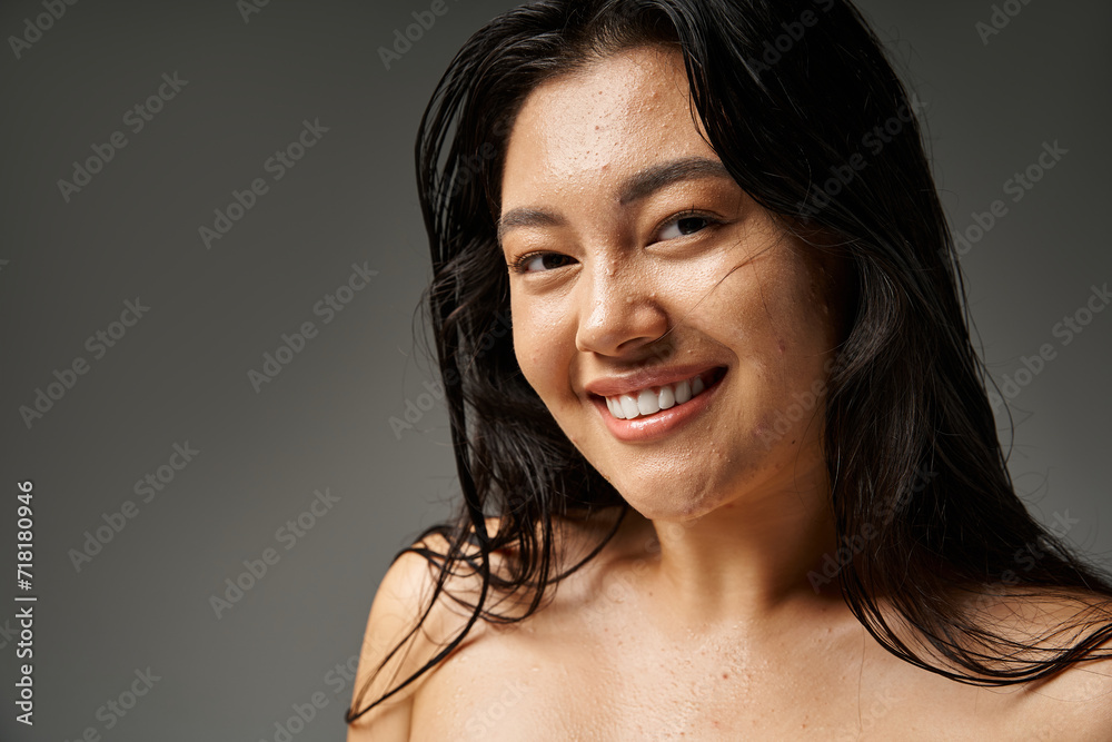 cheerful and young asian woman with blemishes on face and brunette hair on grey background cheerful and young asian woman with blemishes on face and brunette hair on grey background
